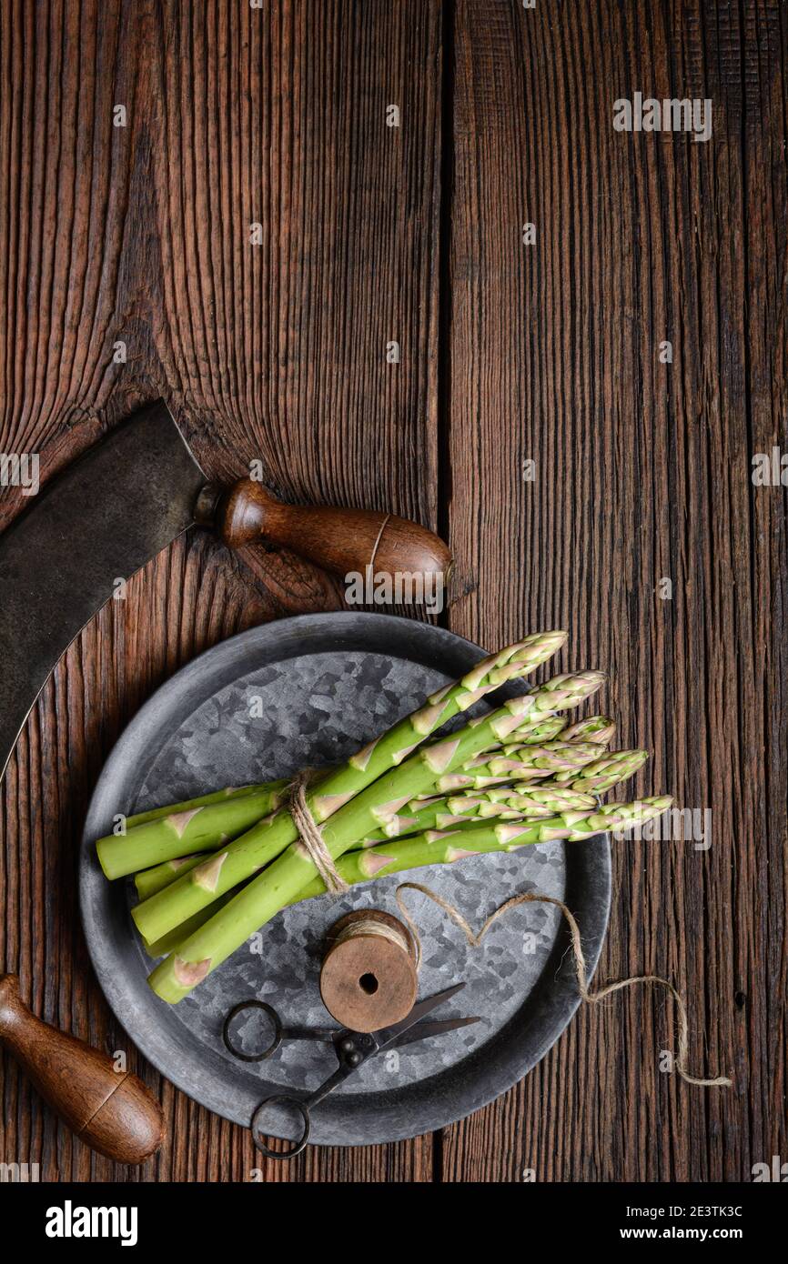 Nutritious vegetable high in antioxidants, a bunch of fresh green asparagus on rustic wooden background with copy space Stock Photo