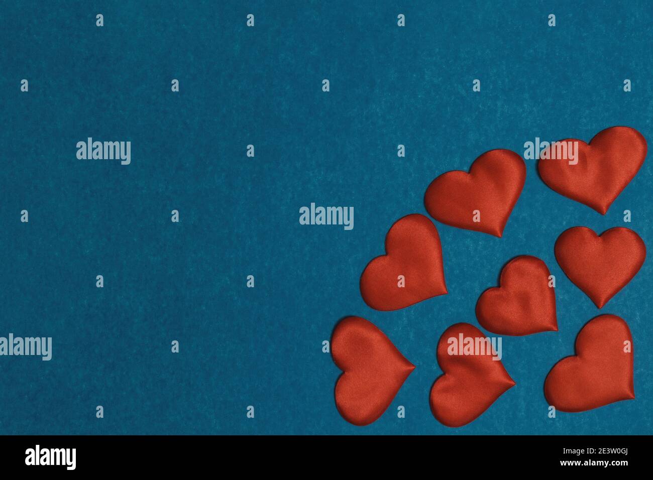 Red textile hearts in corner on blue cardboard background. Valentines Day concept, copy space, flat lay Stock Photo