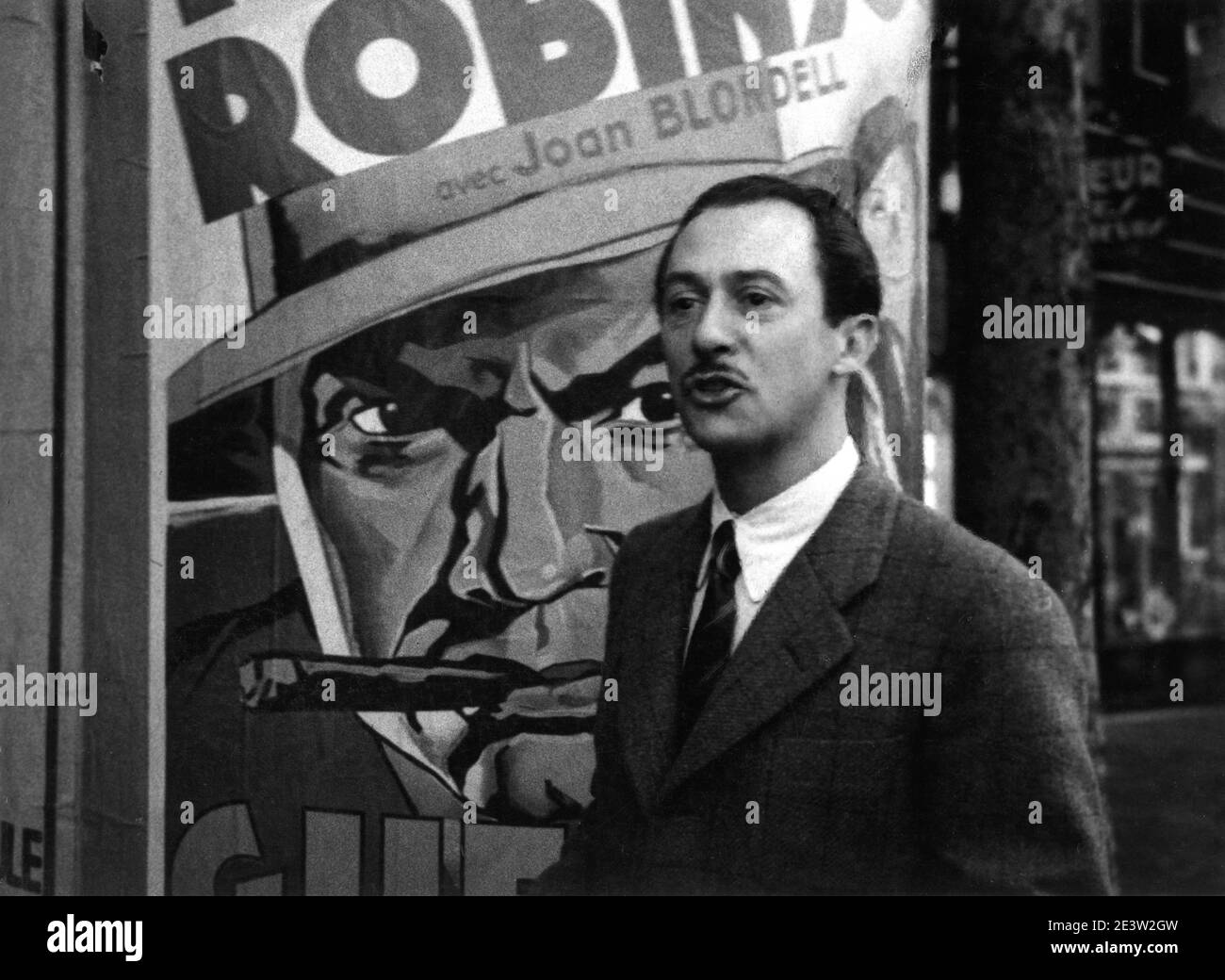 Candid Portrait of Swiss / French Hotelier and Fly Fishing Expert CHARLES RITZ by ANDRE DA MIANO taken in September 1936 in Paris next to a French Movie Poster of EDWARD G. ROBINSON and JOAN BLONDELL in BULLETS OR BALLOTS 1936 director WILLIAM KEIGHLEY Warner Bros. Stock Photo