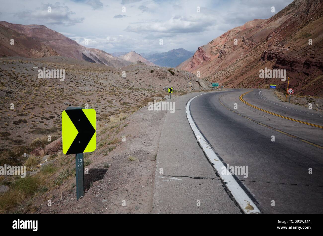 Sharp turn warning sign on mountain road. Highway road in Andes Mountains. Mendoza province, Argentina Stock Photo
