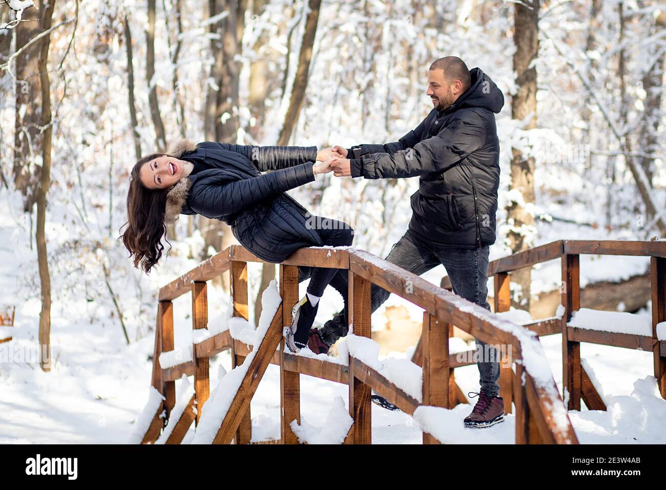 Man and woman in love holding hands on a bridge. Snowy winter ...