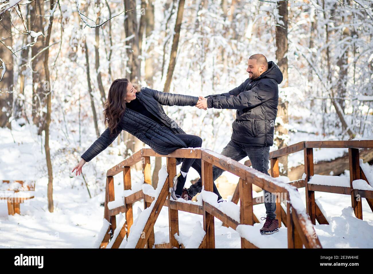 Man and woman in love holding hands on a bridge. Snowy winter ...