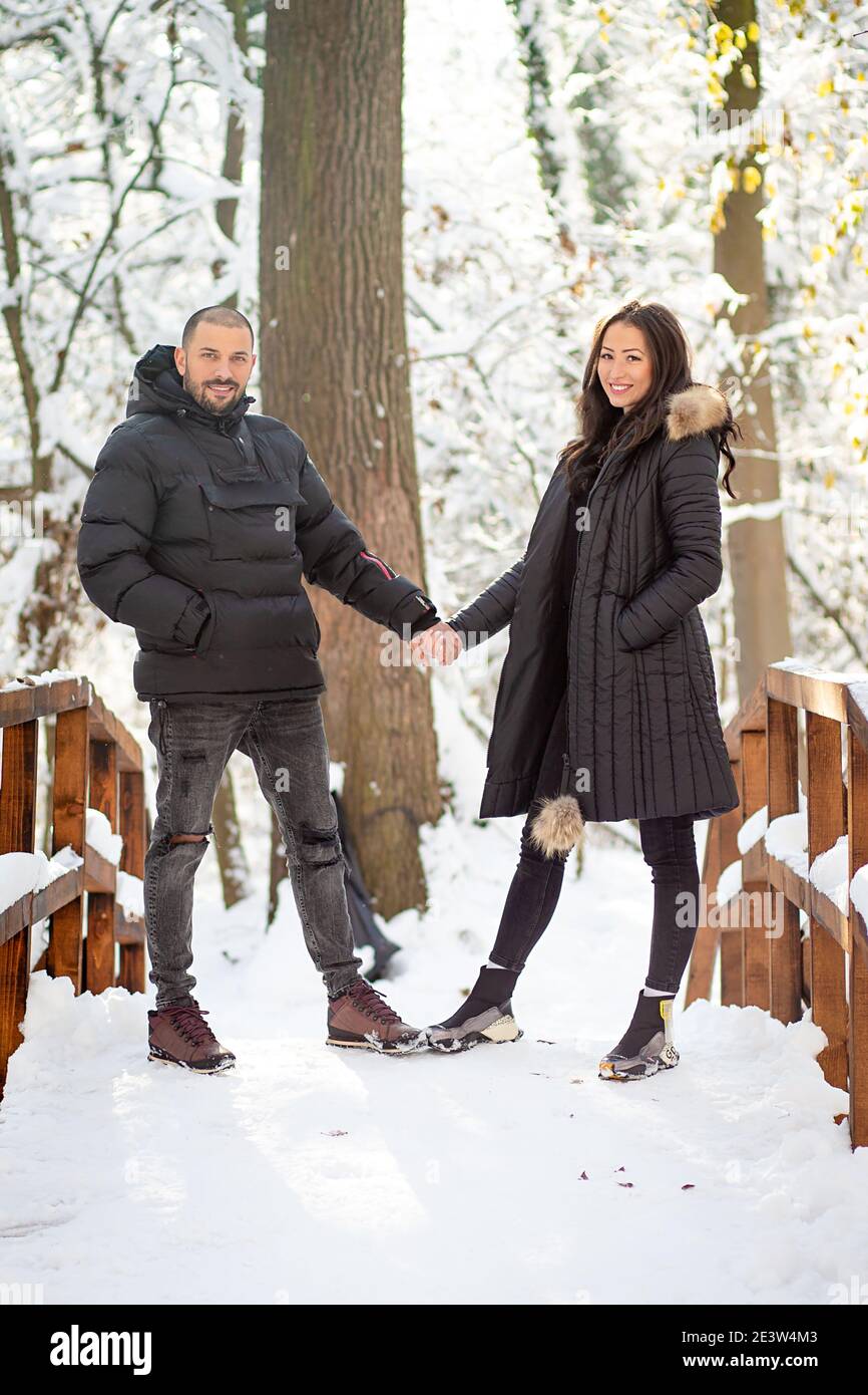Man and woman in love holding hands on a bridge. Snowy winter ...