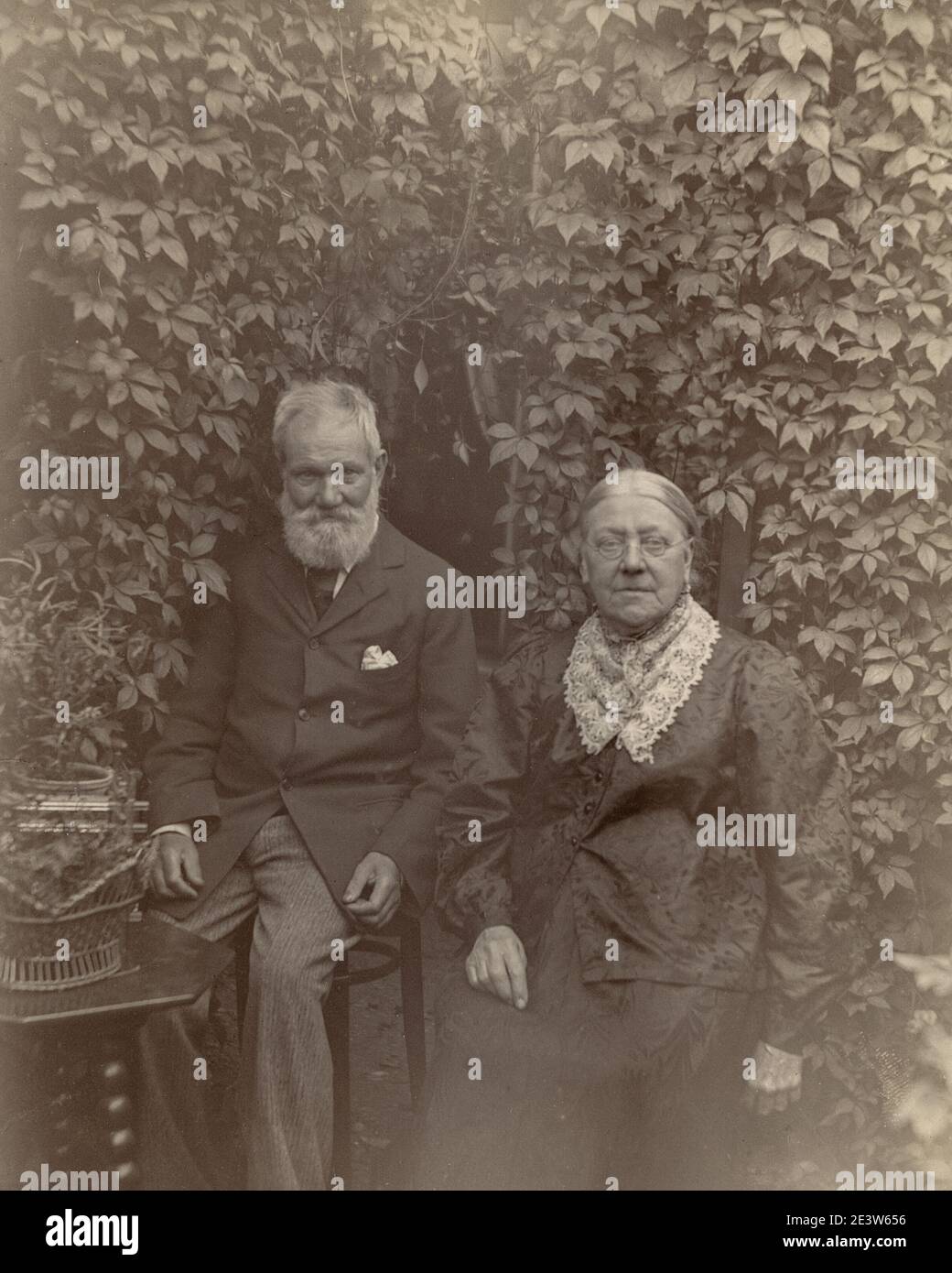 1890s Victorian portrait of and old man and his wife seated in a garden. One of a sequence of ten photographs of friends and family in the same setting. Stock Photo