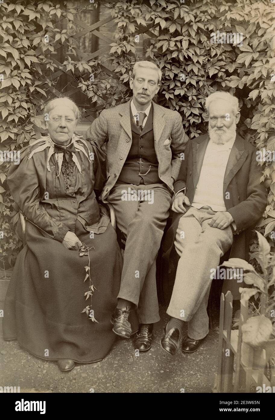 1890s Victorian family portrait showing an unknown man with his parents seated in a garden. One of a sequence of ten photographs of friends and family in the same setting. Stock Photo