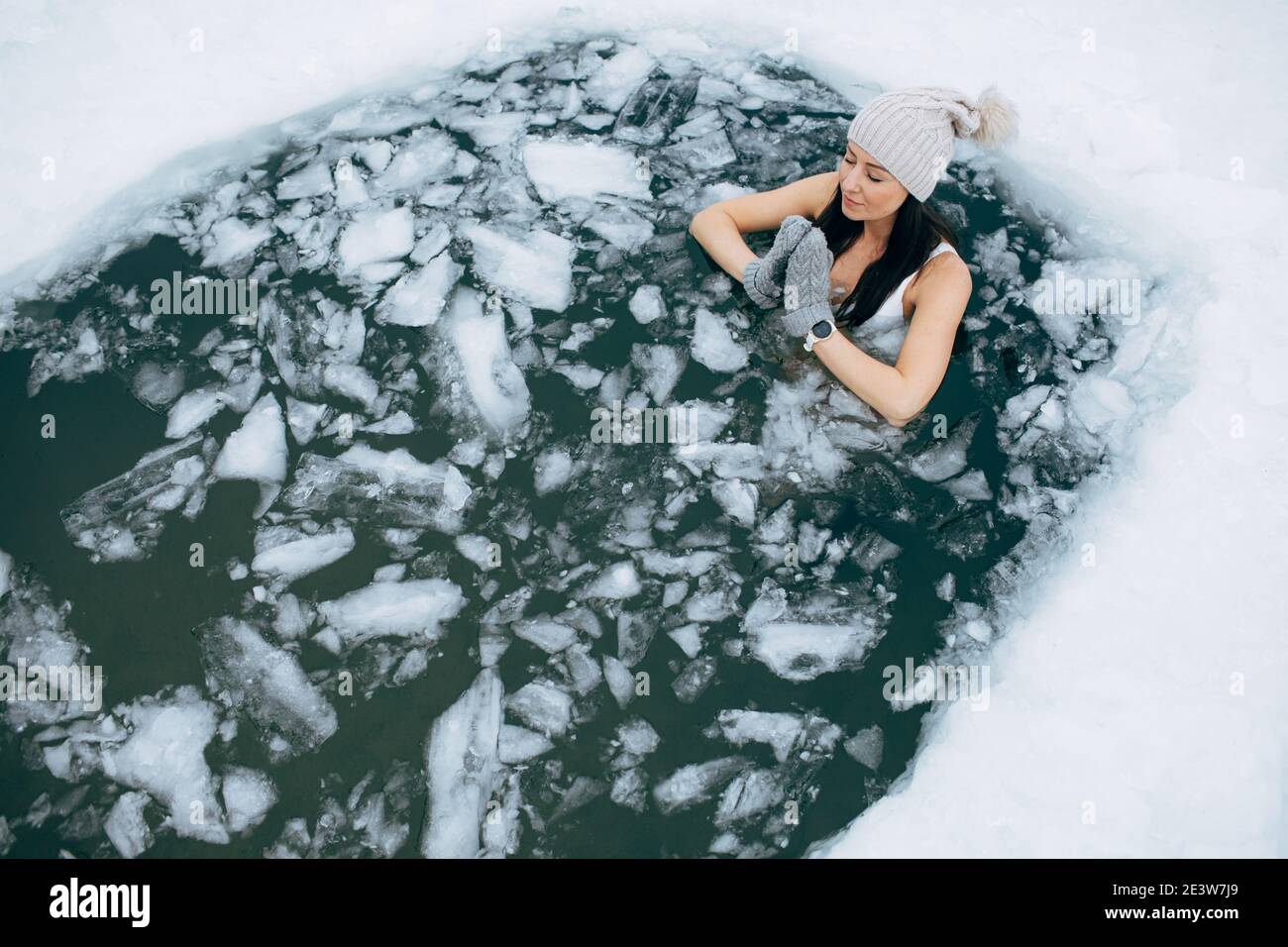 Winter swimming. Woman in frozen lake ice hole. How to swim in cold