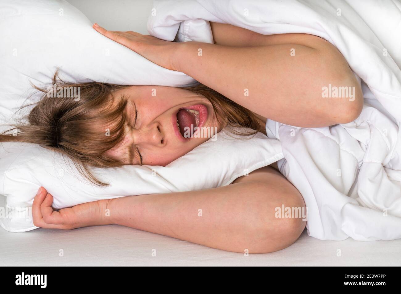 Young woman with head under her pillow trying to sleep Stock Photo Alamy