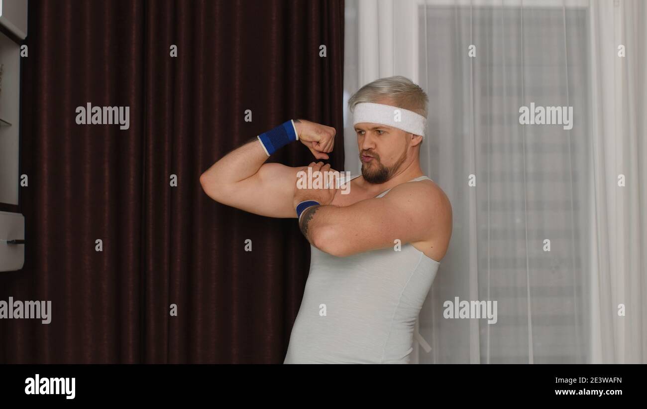 Funny bodybuilder sportsman guy couch showing biceps. Stylish hipster