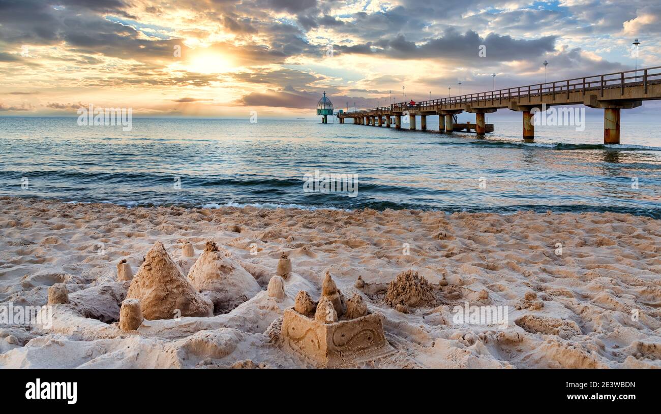 Pier and beach with sand castles in foreground in Zinnowitz at sunset. Baltic Sea, island Usedom, Germany Stock Photo