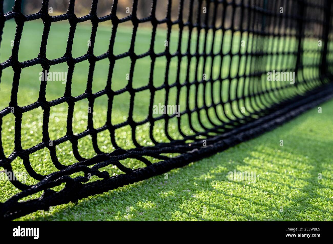 Selective focus of a black net to play paddle or tennis on green artificial grass Stock Photo