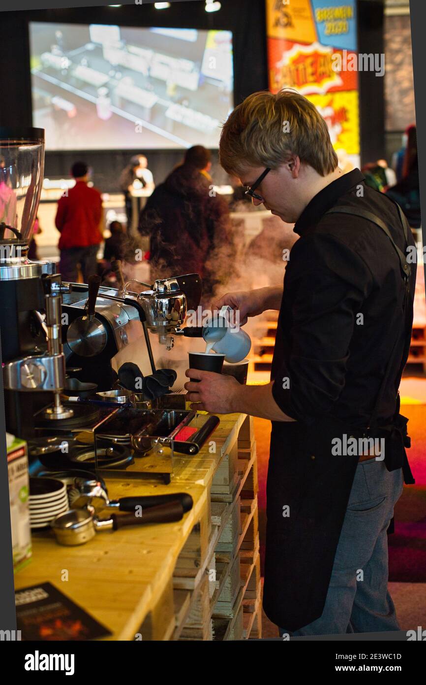 Barista pouring steamed milk into coffee cup making latte art. Stock Photo