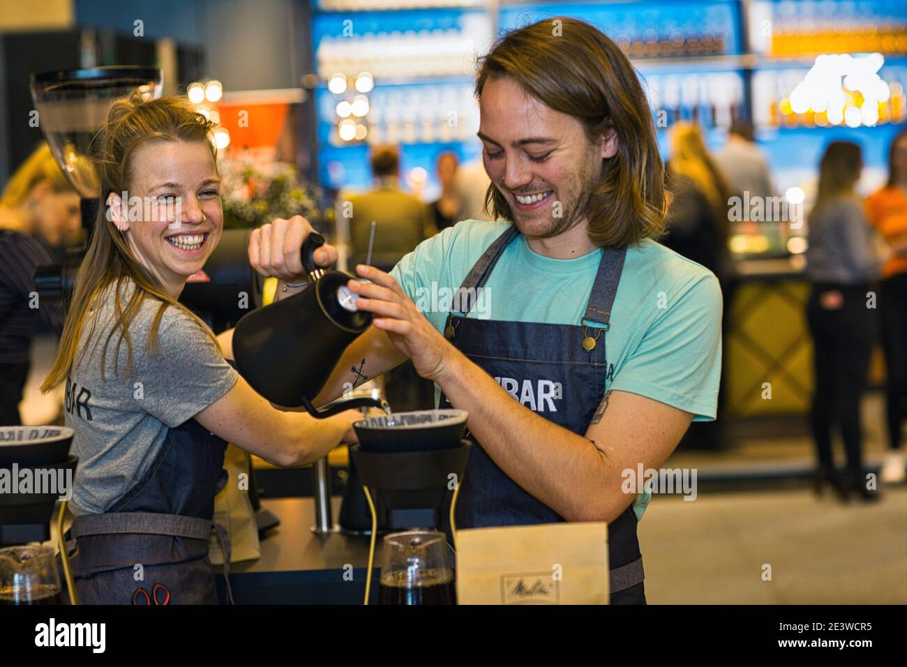 Happy female and male baristas pouring coffee through filter Stock Photo
