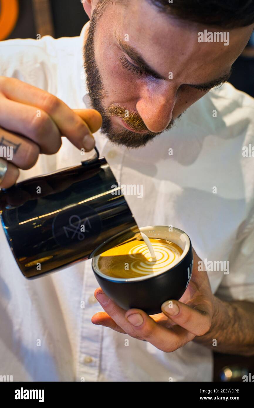 Yuri Marschall latte art champion from Germany pouring steamed milk into coffee cup making latte art. Stock Photo