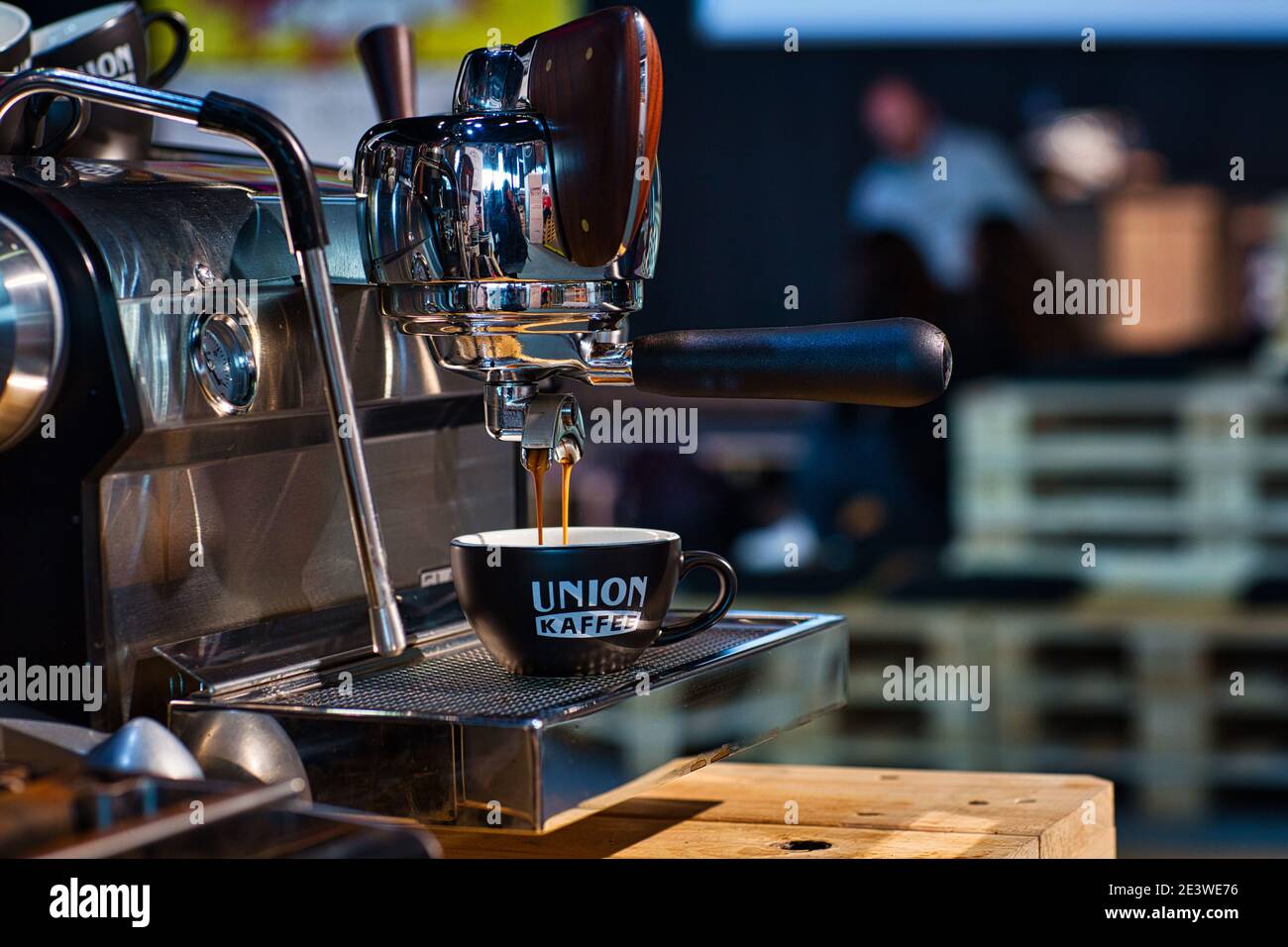 Fresh coffee dripping from portafilter of coffee machine into cup. Stock Photo