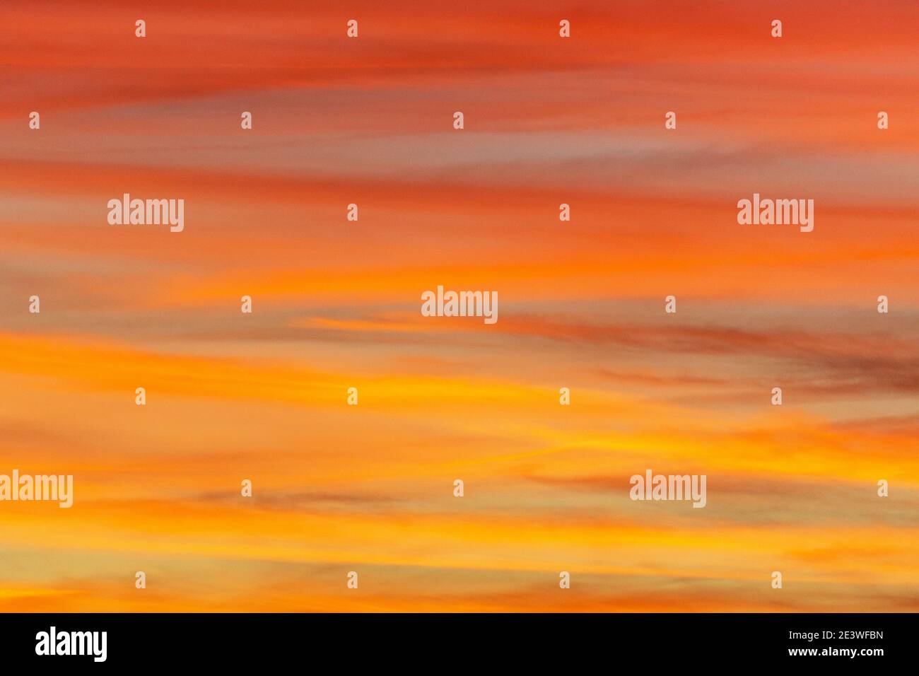 Dusk's setting sun creates clouds with stripes colored hot pink and orange sherbet. Stock Photo