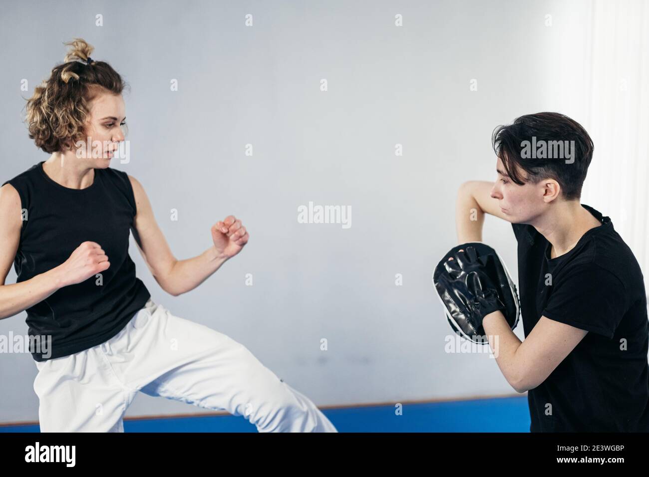 Closeup of barefoot woman leg practicing kicking with taekwondo coach