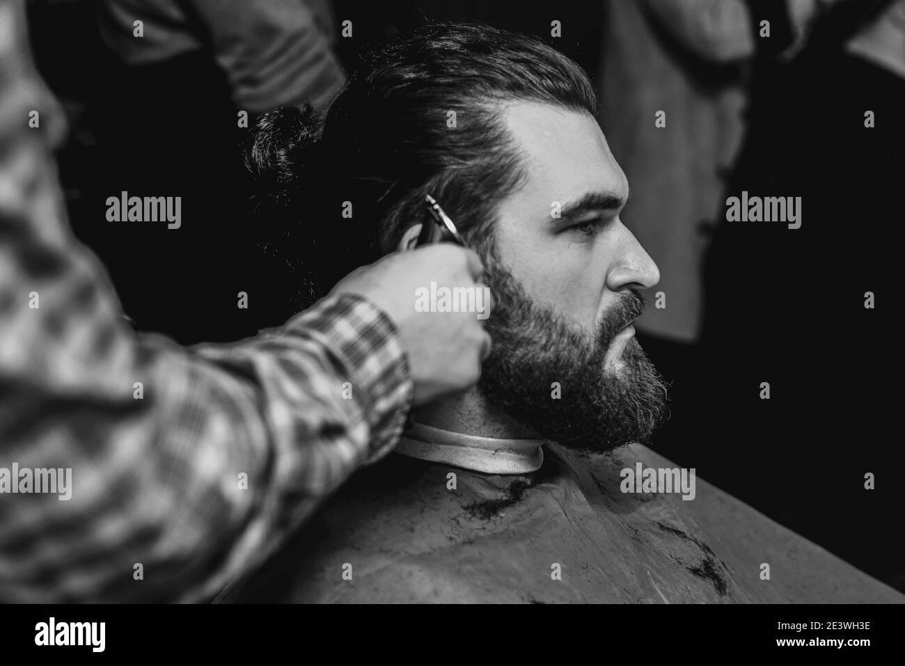 Black and white photo of man having haircut in barbershop. Stock Photo