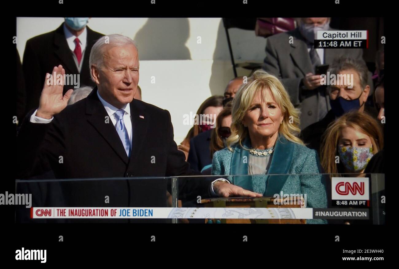 A CNN television screen shot of U.S. President Joe Biden being sworn in at his 2021 inauguration in Washington, D.C. with his wife, Dr. Jill Biden. Stock Photo