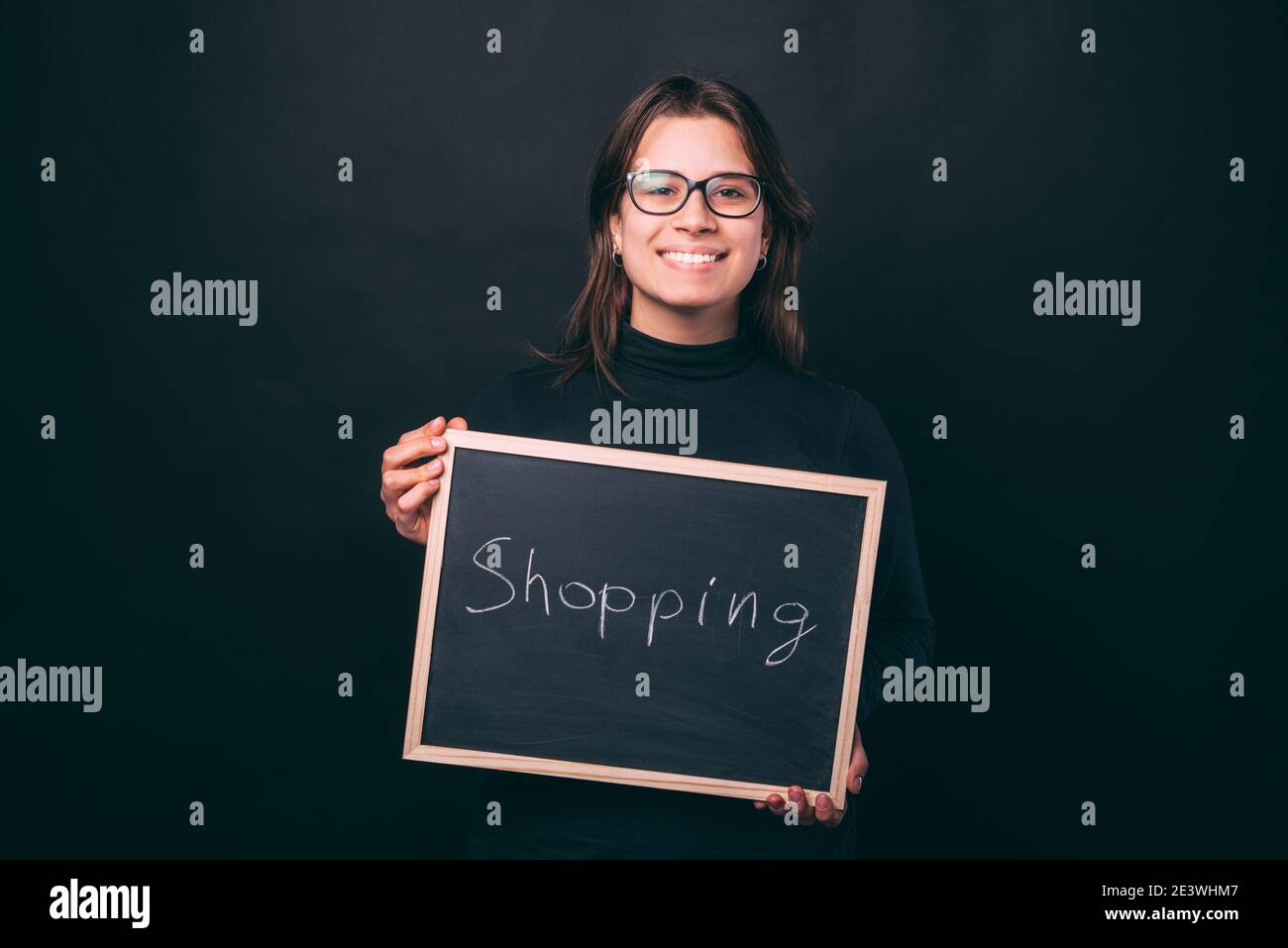 Photo of smiling woman holding chalk board with SHOPPING word. Stock Photo