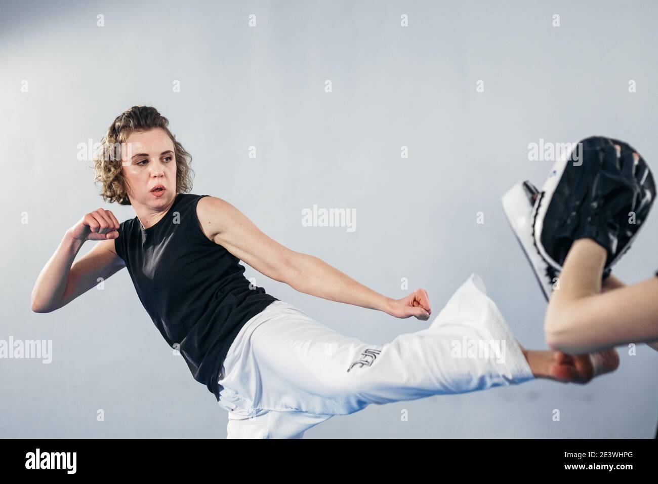 Closeup of barefoot woman leg practicing kicking with taekwondo coach