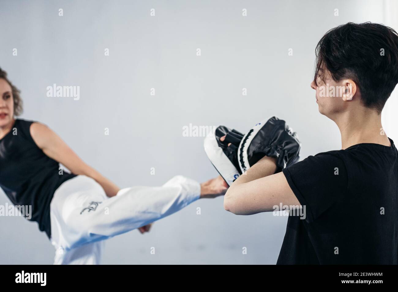 Closeup of barefoot woman leg practicing kicking with taekwondo coach