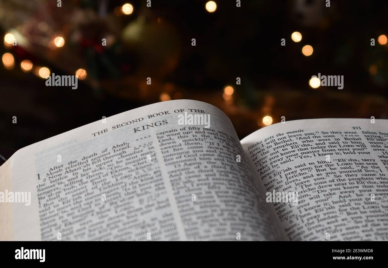Bible page turned to the First Book of Kings with soft lights in the background Stock Photo