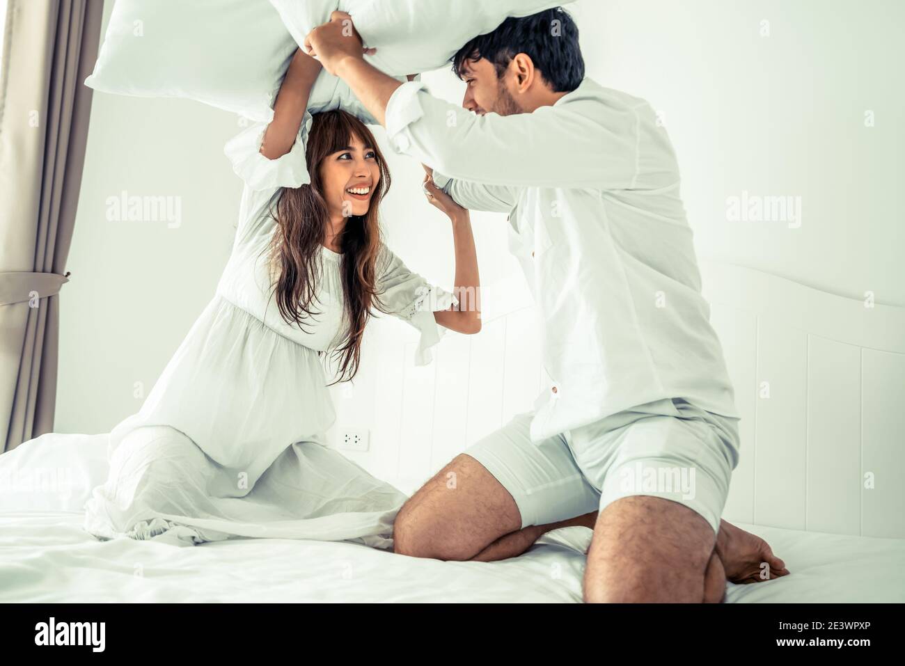 Happy couple do pillow fighting in home bedroom Stock Photo Alamy