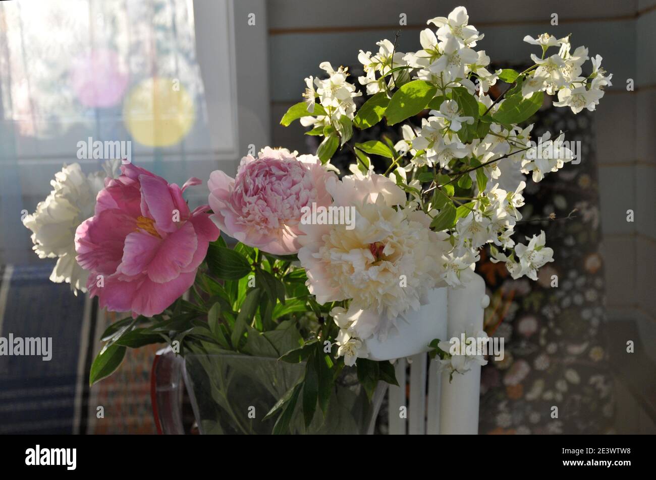 summer bright bouquet with peony and Jasmine on windowsill in the sunshine Stock Photo