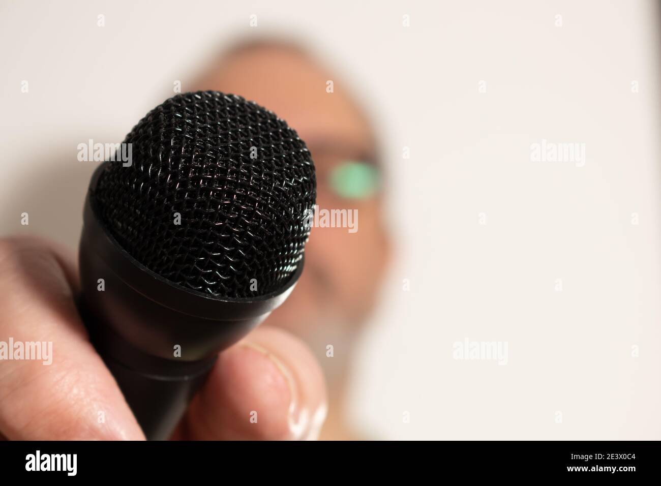 A man's hand holding a black microphone. Concept of communication, interviews, virtual dialogues. Stock Photo