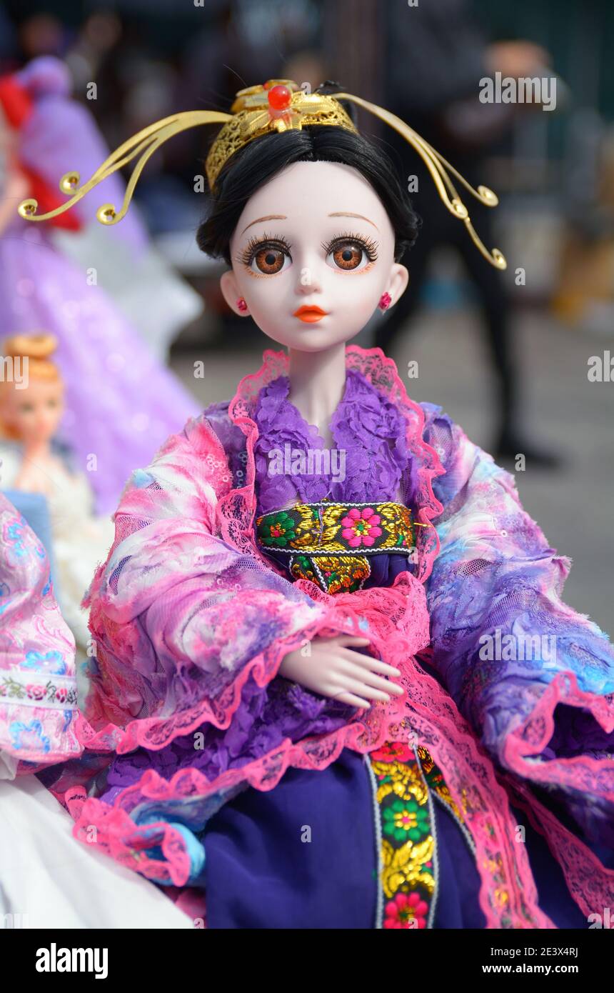 Items for sale at the Sunday antique market in Yuehe old street, Jiaxing. A pretty doll in colourful clothes. Stock Photo