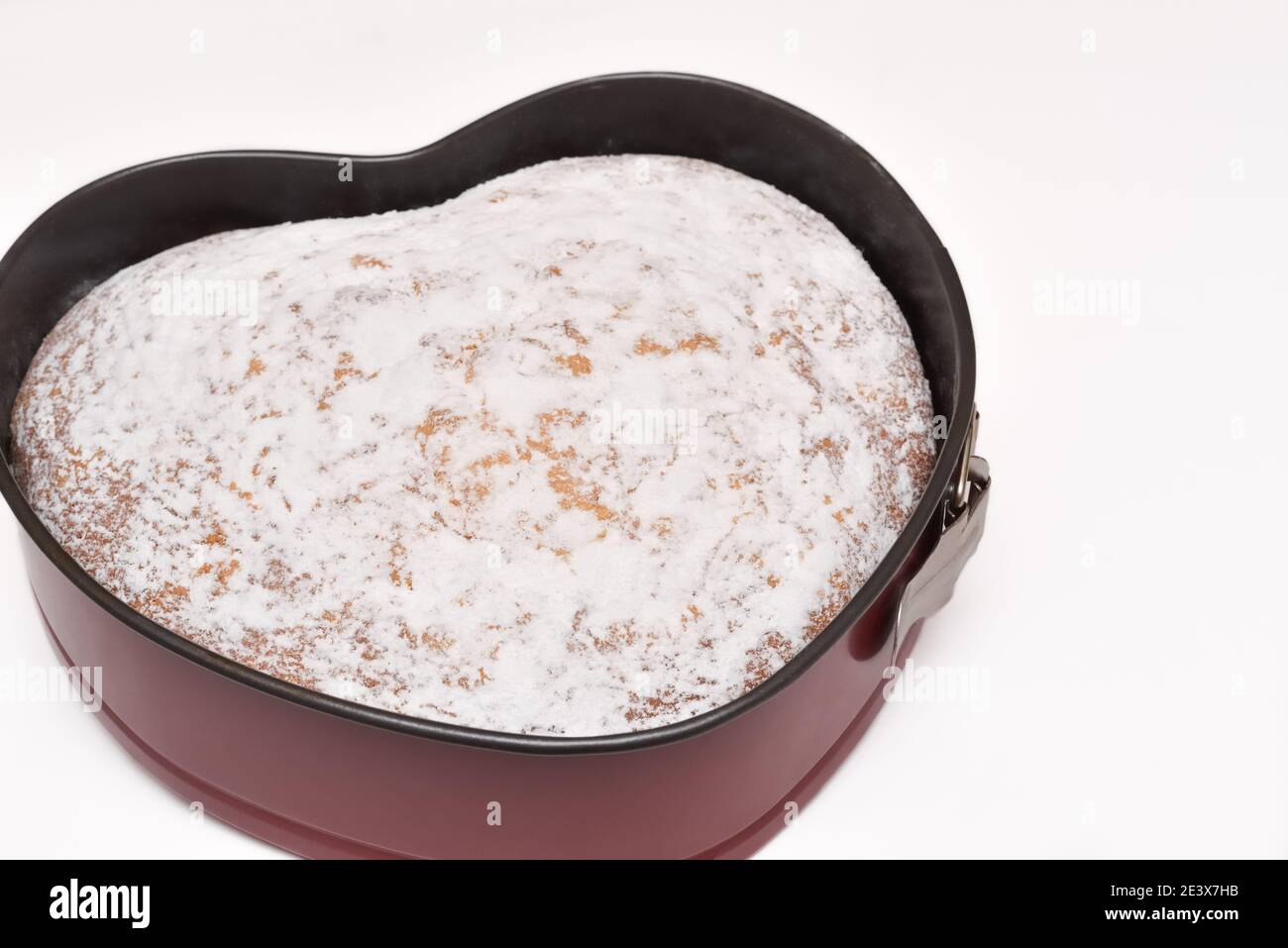 springform pan with freshly baked heart shaped cake dusted with