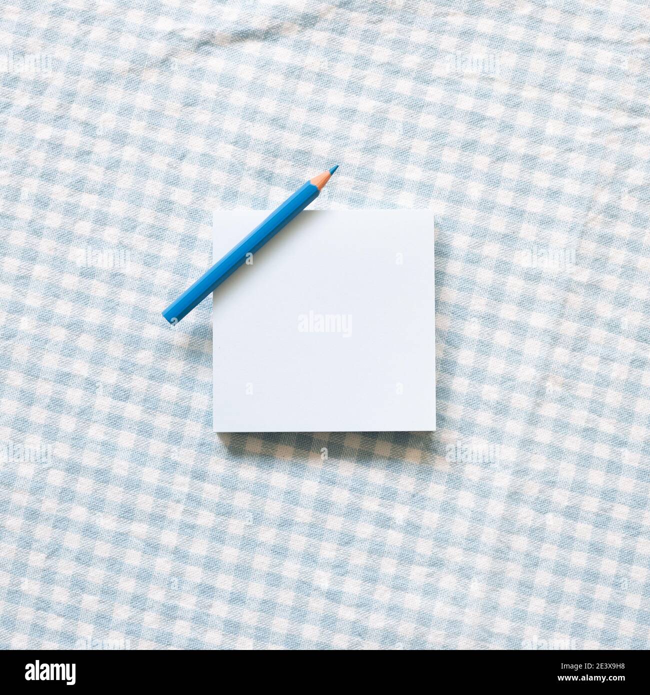 Blue memo pad with colored pencil on blue check pattern fabric background. top view, copy space Stock Photo