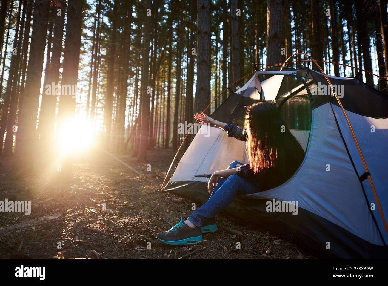 Morning camping in the forest. Young woman traveller sitting in white