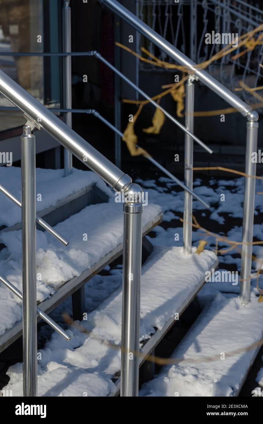 Stainless steel railings and steps in the snow. Exterior entrance to ...