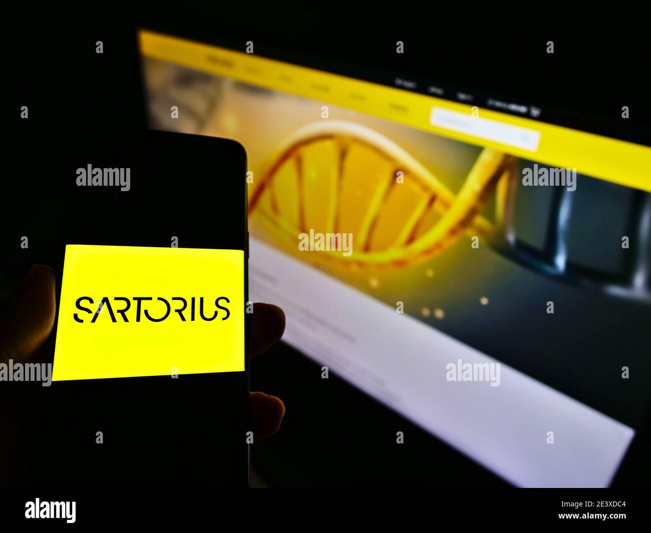 Person holding cellphone with company logo of German pharmaceutical and laboratory equipment supplier Sartorius AG. Focus on smartphone screen. Stock Photo