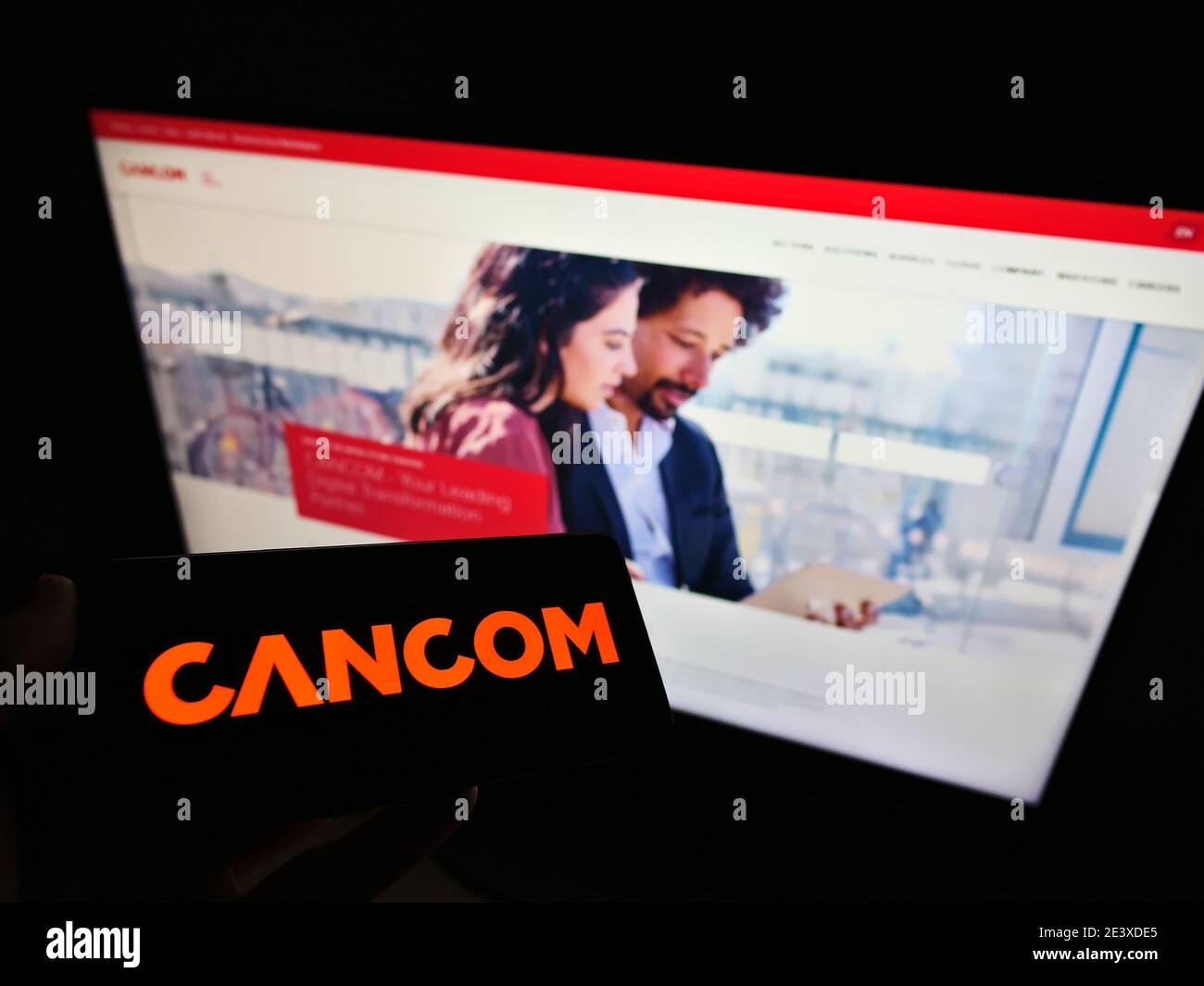 Person holding smartphone with logo of German IT services company and system house Cancom SE on screen. Focus on right of mobile phone display. Stock Photo