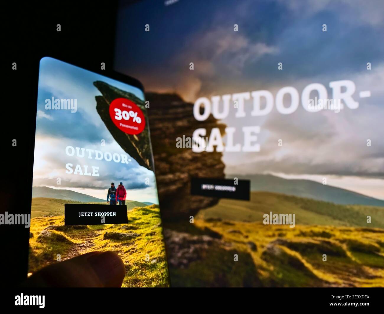 Landing page of online shop of German outdoor clothing retailer Schöffel. Focus on black button on mobile phone screen. Unmodified photo. Stock Photo