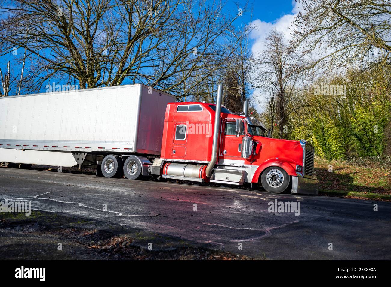 https://c8.alamy.com/comp/2E3XE0A/bright-red-american-idol-classic-big-rig-semi-truck-tractor-with-chrome-accessories-and-vertical-exhaust-pipes-and-dry-van-semi-trailer-standing-on-th-2E3XE0A.jpg