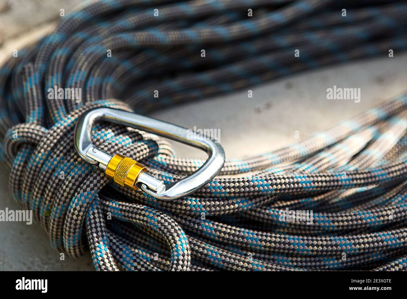 Coiled climbing rope and steel carabiner. Mountain climbing equipment