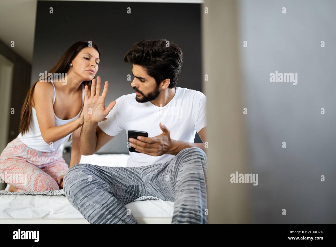 Jealous wife spying her husband mobile phone Stock Photo