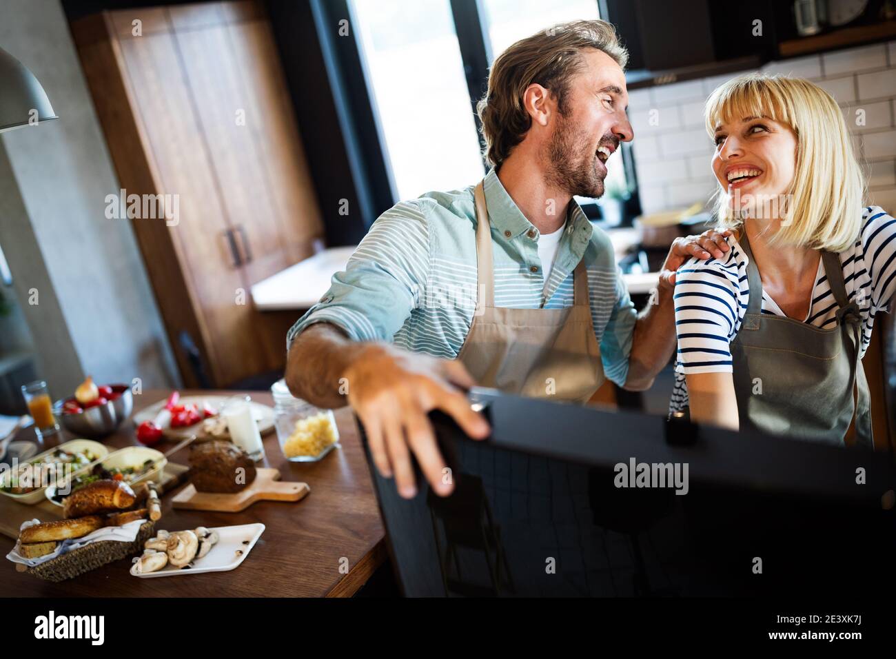 Beautiful young couple is talking and smiling while cooking healthy ...