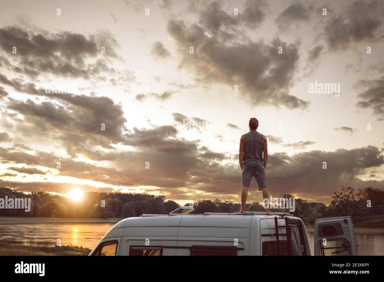 Man enjoying the sunset on the roof of his camper van Stock Photo