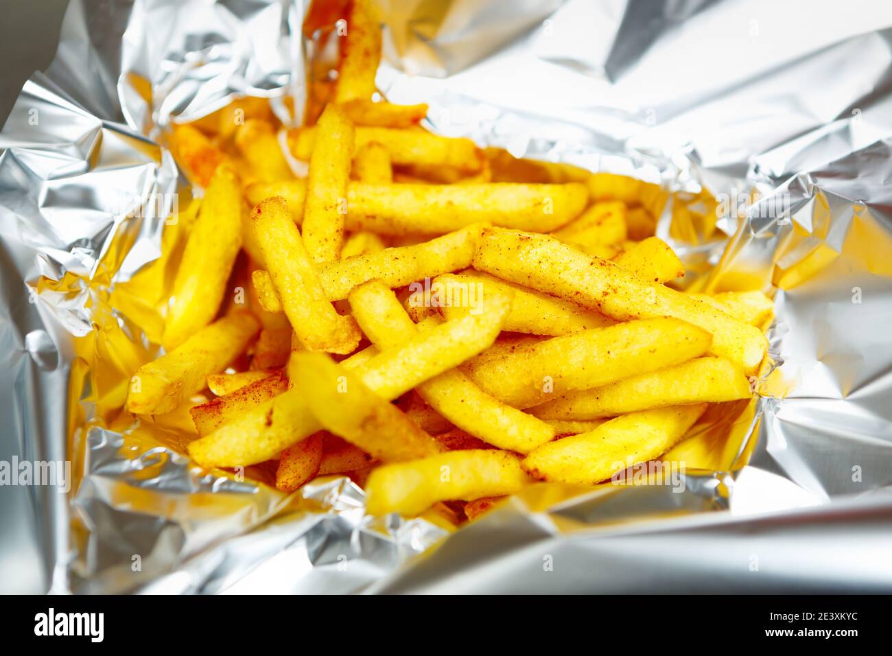 Golden French fries delivered in tinfoil for dinner.Delicious potato chips delivery from fast food restaurant Stock Photo