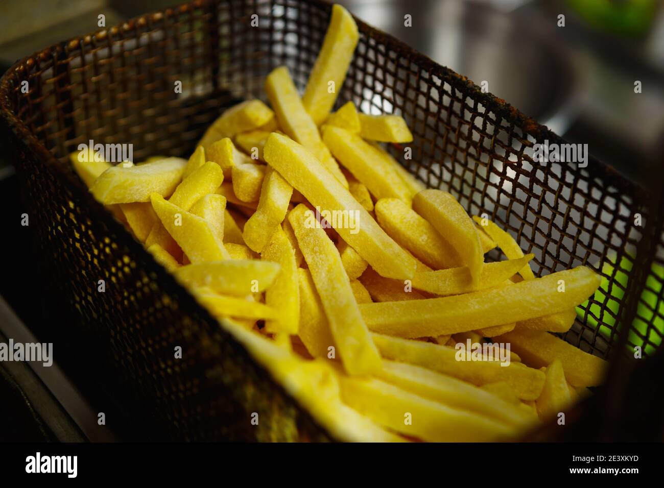 Frozen uncooked French fries in fryer oven prepared for cooking for