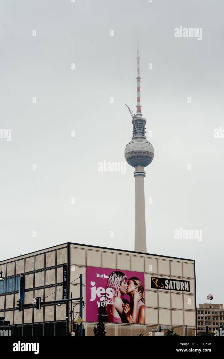 Berlin, Germany - July 30, 2019: Saturn store with two girls kissing on billboard in Karl-Marx-Allee against Telecommunications tower a foggy day Stock Photo