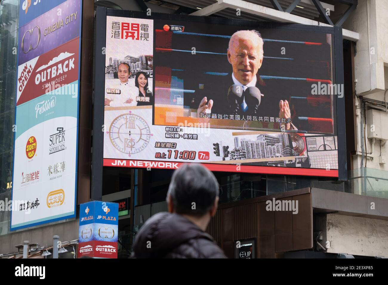 A man is seen watching the news report of the inauguration of U.S. President Joe Biden on a large screen. Stock Photo