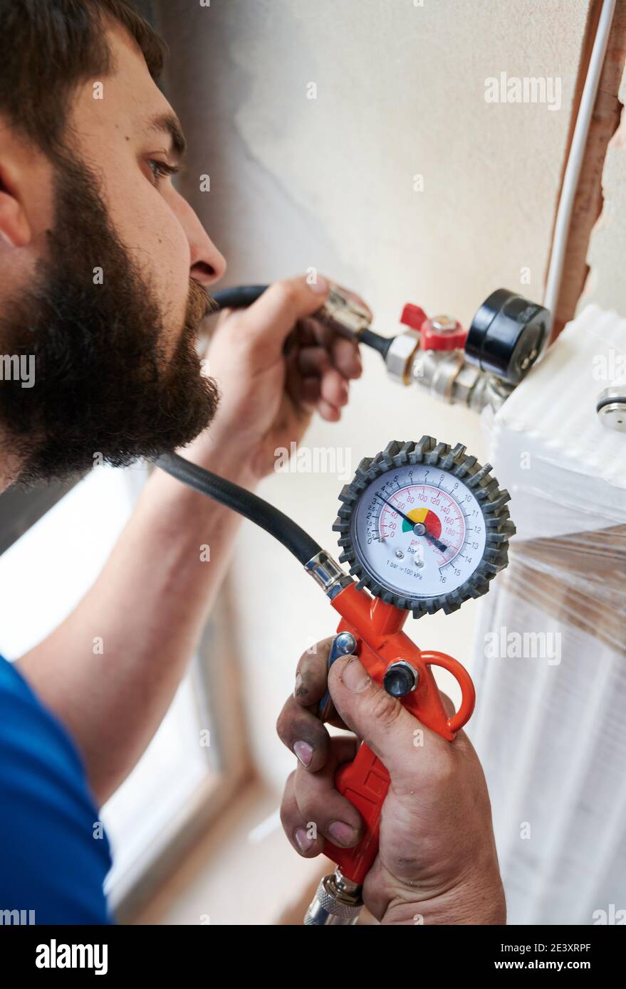 Close up of bearded man filling pipes with pressurized air to inspect