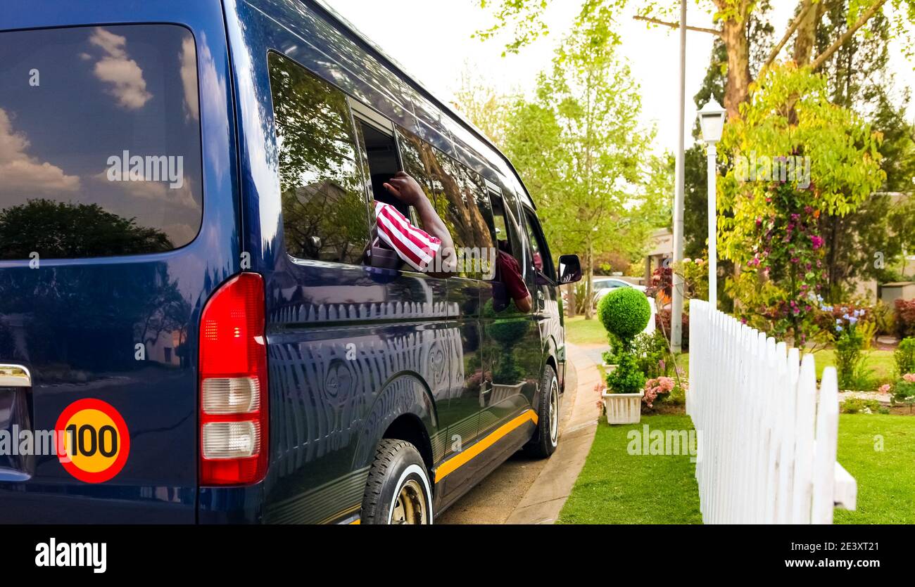 Minibus taxi van parked outside a house in a wealthy neighbourhood with an arm hanging out Stock Photo