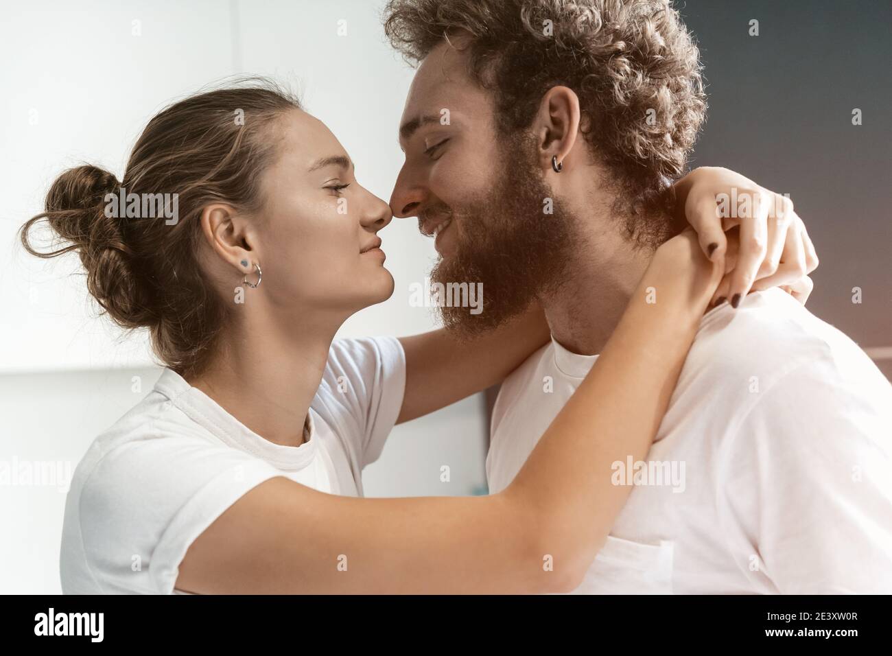Young man kissing his wife standing at the kitchen. Morning kiss to a wife,  young couple flirting in the kitchen. Portrait of romantic couple in love  Stock Photo - Alamy