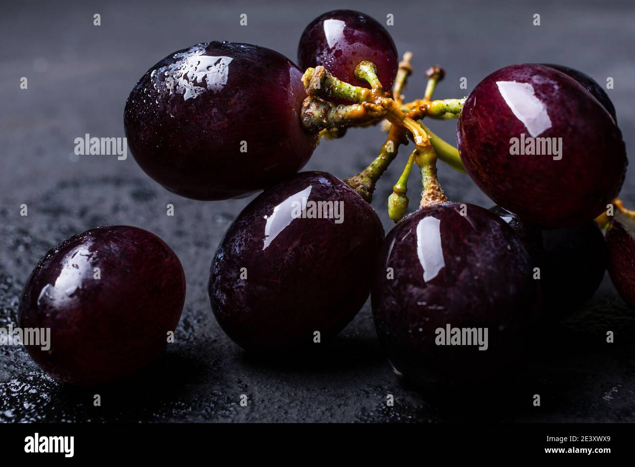 in the foreground a bunch of black table grapes Stock Photo